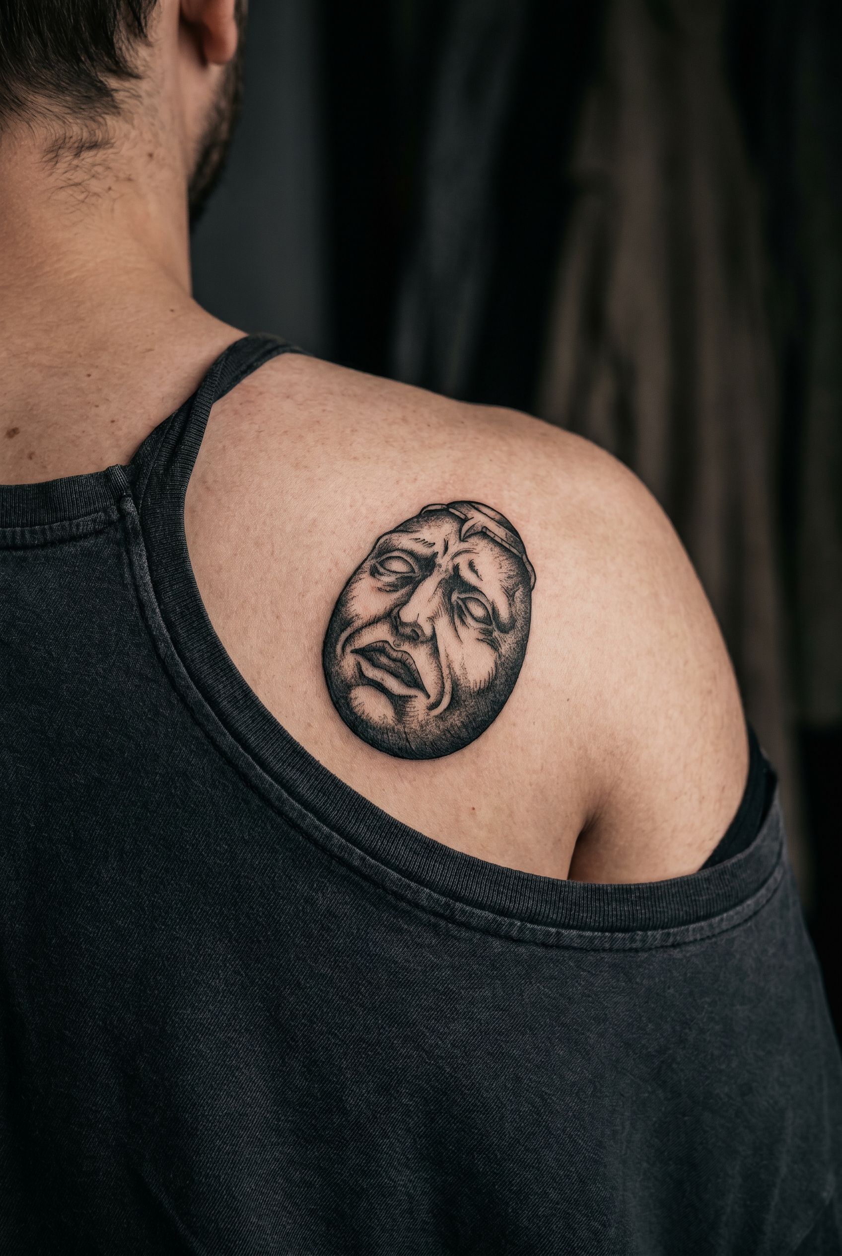 Tatouage du Béhérit, relique en forme d'œuf au visage déformé, sur le haut du dos