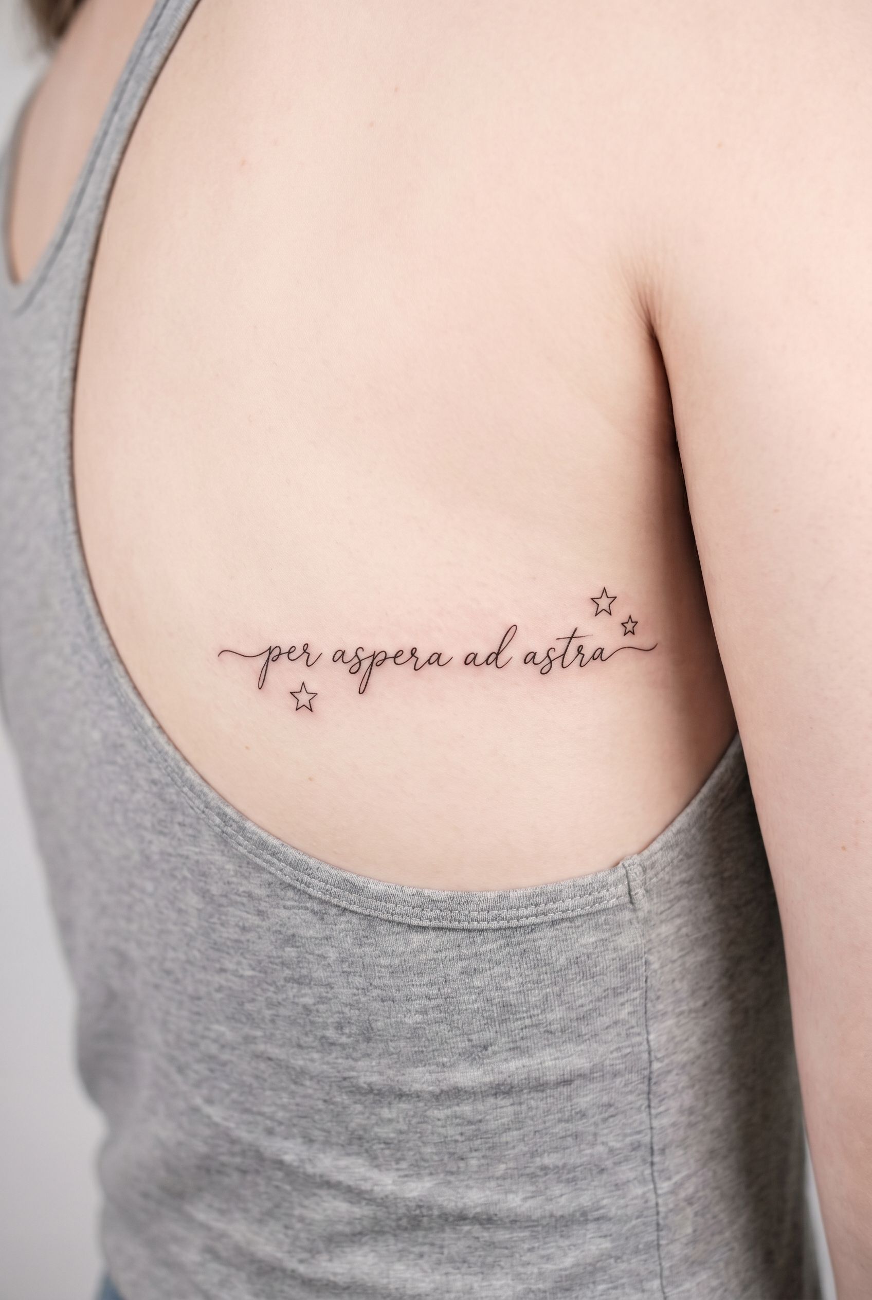 Tatouage de la phrase latine Per aspera ad astra sur les côtes