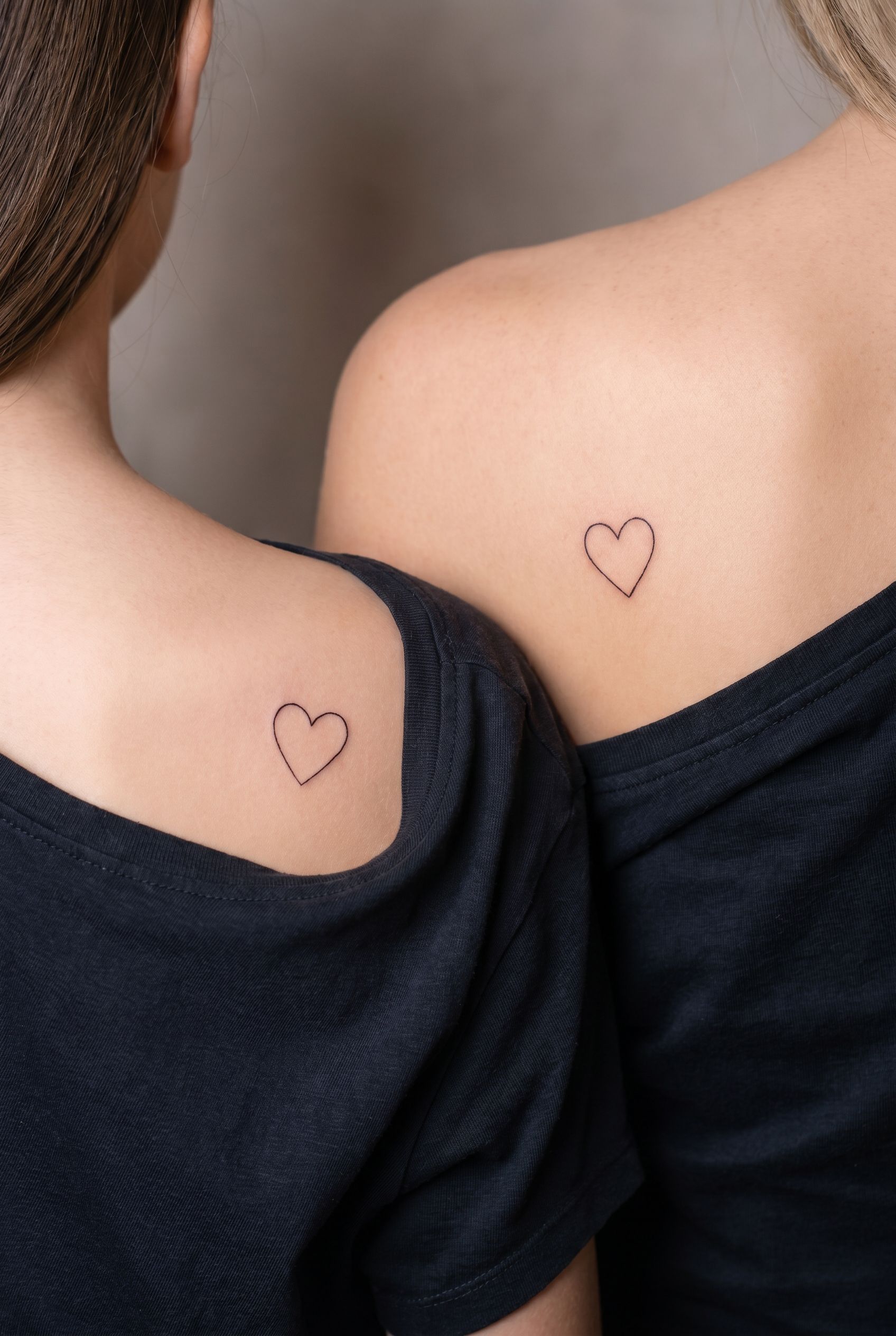 Deux petits cœurs assortis tatoués sur l'omoplate d'une mère et de sa fille