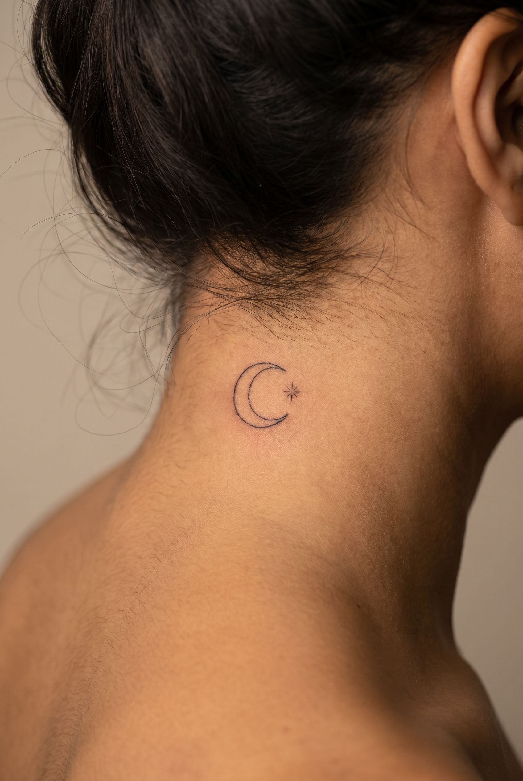 Tatouage d'un croissant de lune fin sur la nuque d'une femme