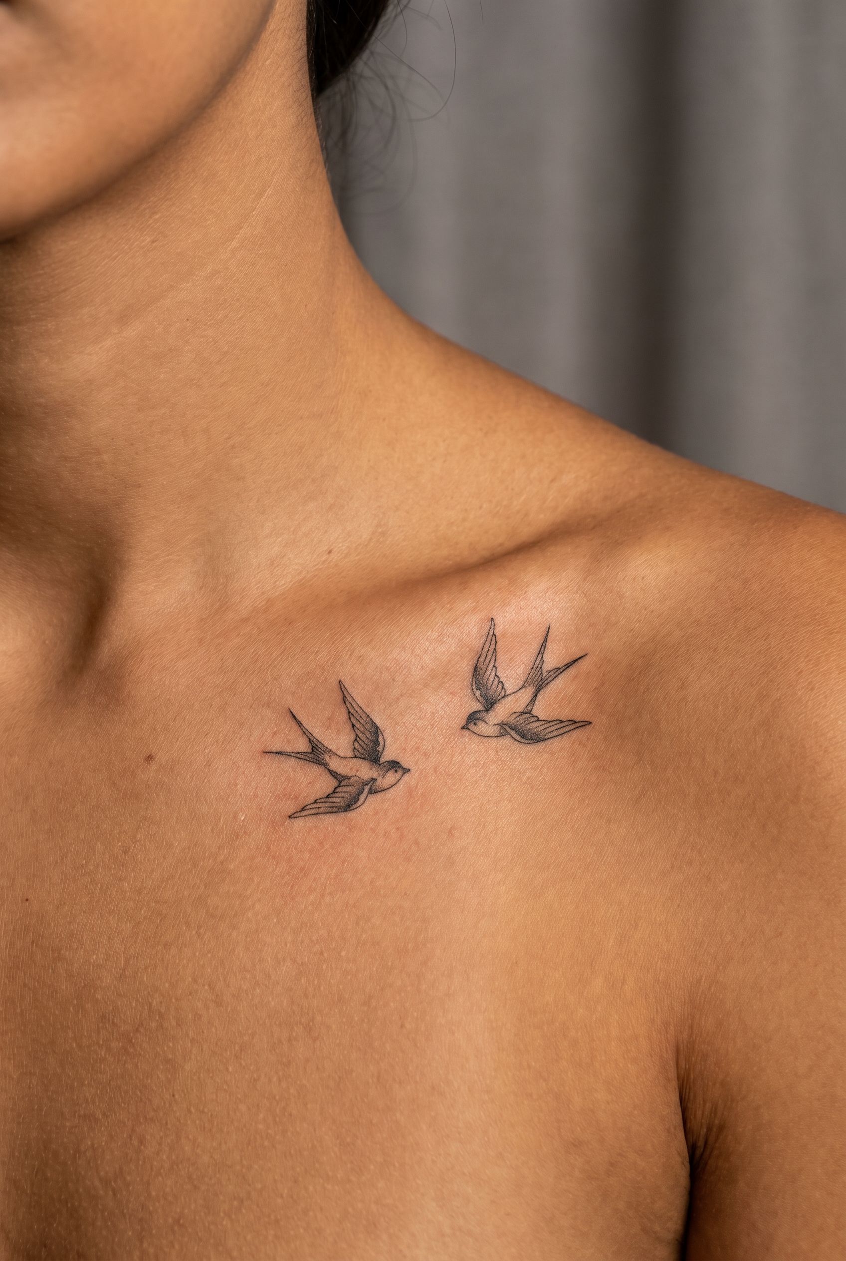 Deux hirondelles tatouées sur la clavicule d'une femme