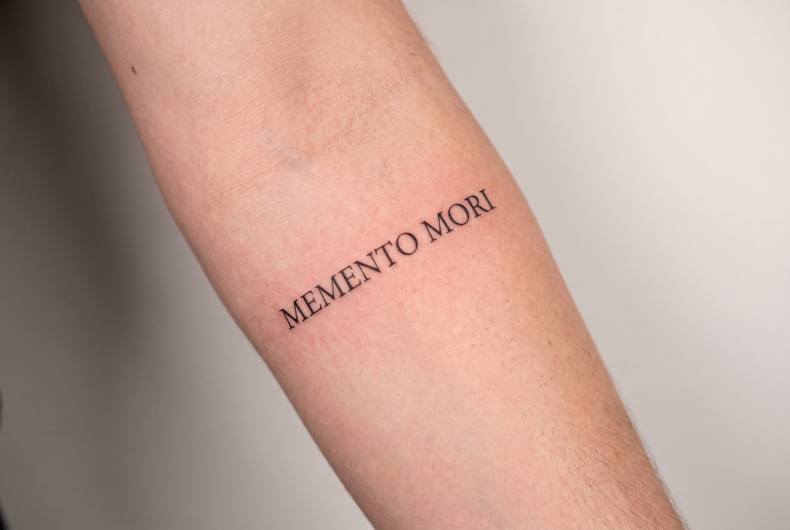 Tatouage phrase en latin le long de l'avant-bras