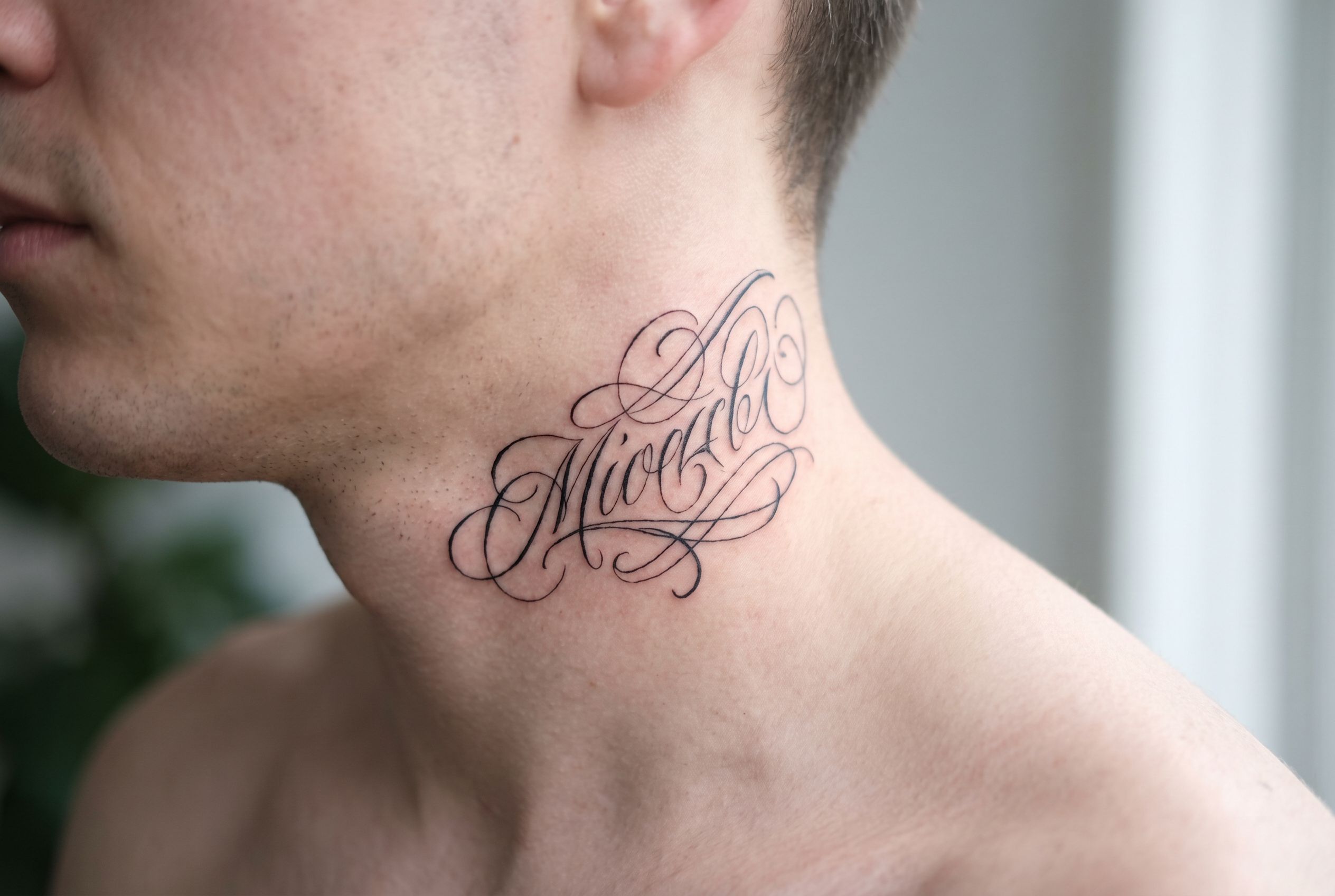 Tatouage lettrage sur le côté du cou d'un homme