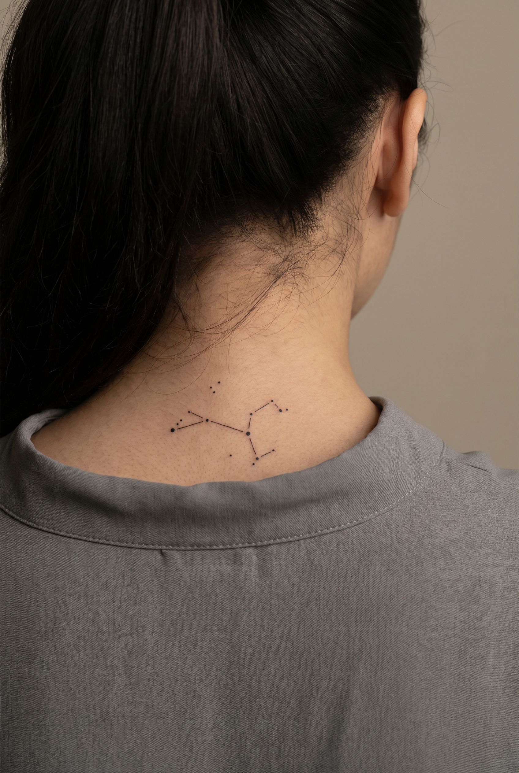 Tatouage minimaliste de points et lignes evoquant une constellation sur le haut du dos